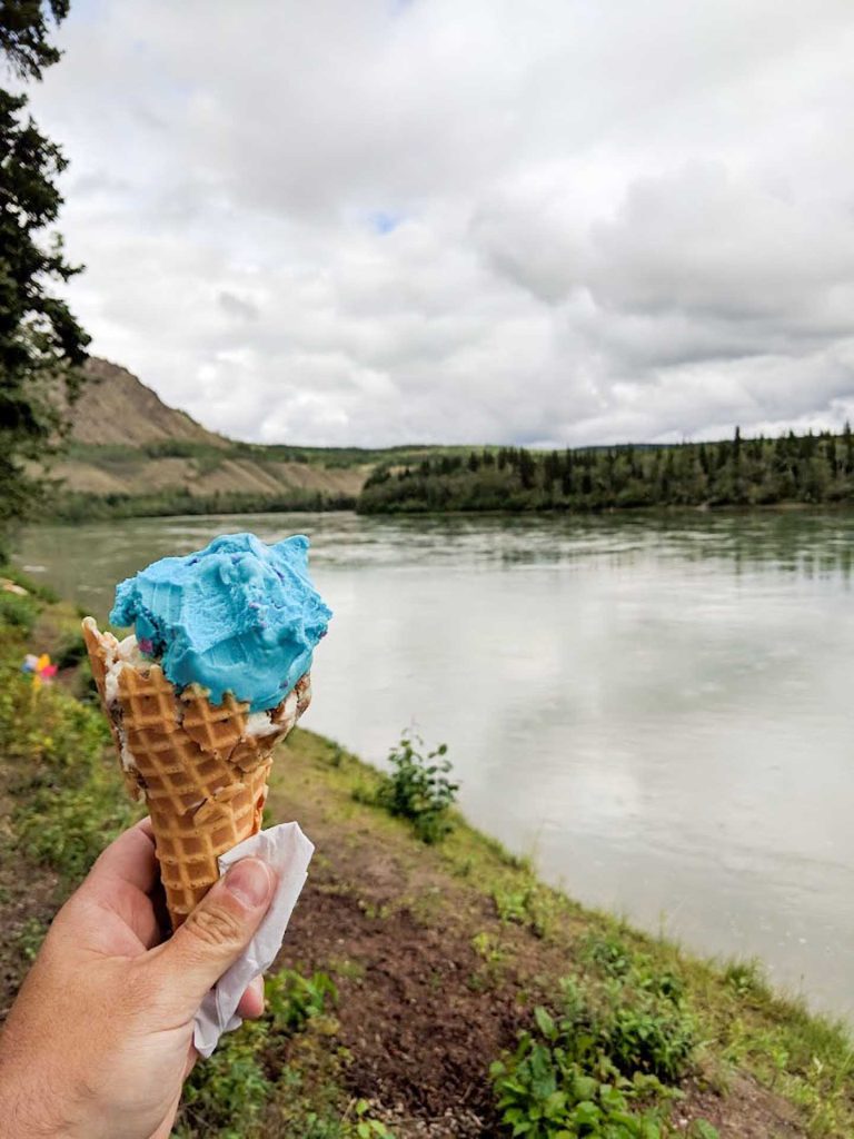 hand holding an ice cream, body of water on the background